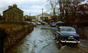 At Parkside, near Milnthorpe, a 1965 Volvo eases its way through the floodwater.