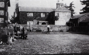 The tractor seen on the left of this picture was the first one on Ryefield Farm. The shadow  in the foreground, from the barn behind, runs to the stables, from where Kenneth Orchard had to dash to safety from the geese. The lower building in the yard is where the Lister and pump were housed. The coat with the cartridges was hung on the wall next to the scullery yard gate.