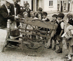 Watched by a crowd, ofyoungsters amused by theflying sparks, a scissors-grinder goes to work sharpening another pair.