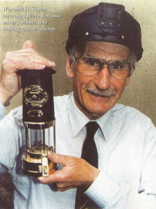 Warwick H. Taylor, wearing a Bevin Boy-issue miner's helmet, and holding a miner's lamp.